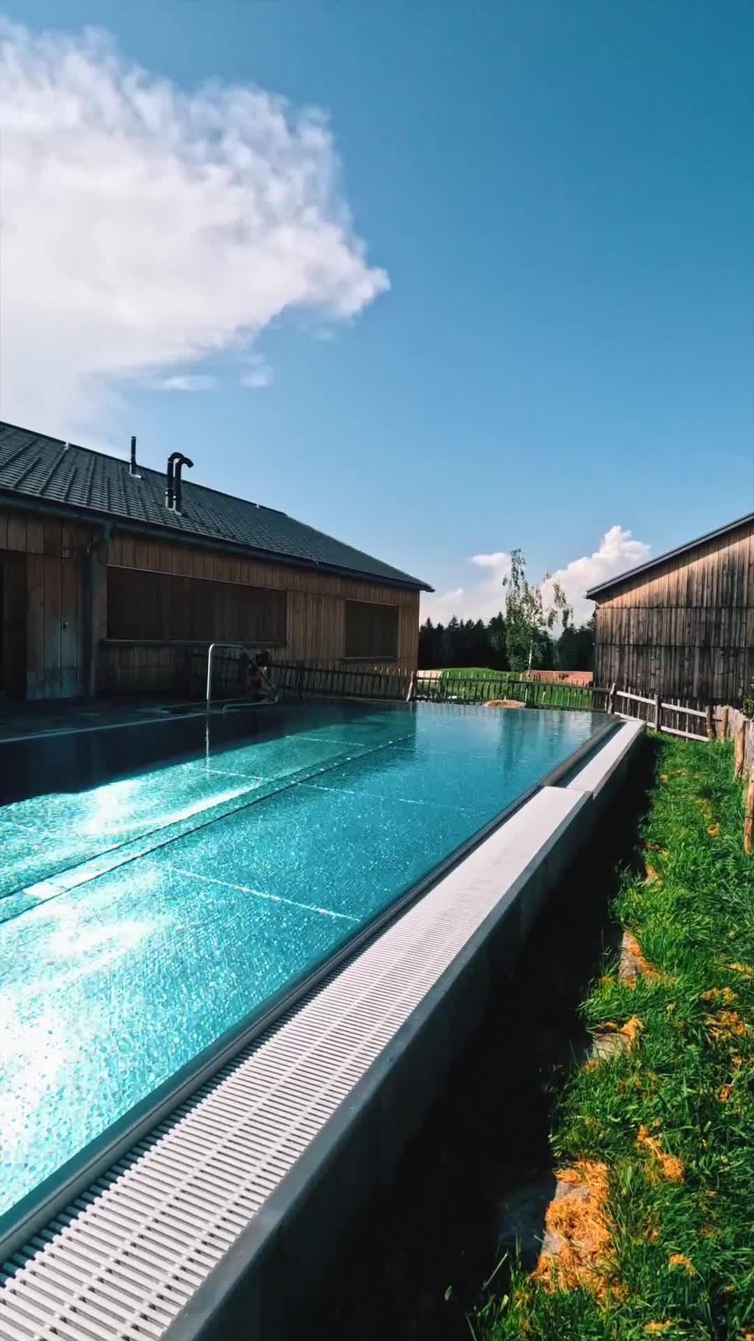 Infinity pool beside timber lodge cabins under a clear blue sky