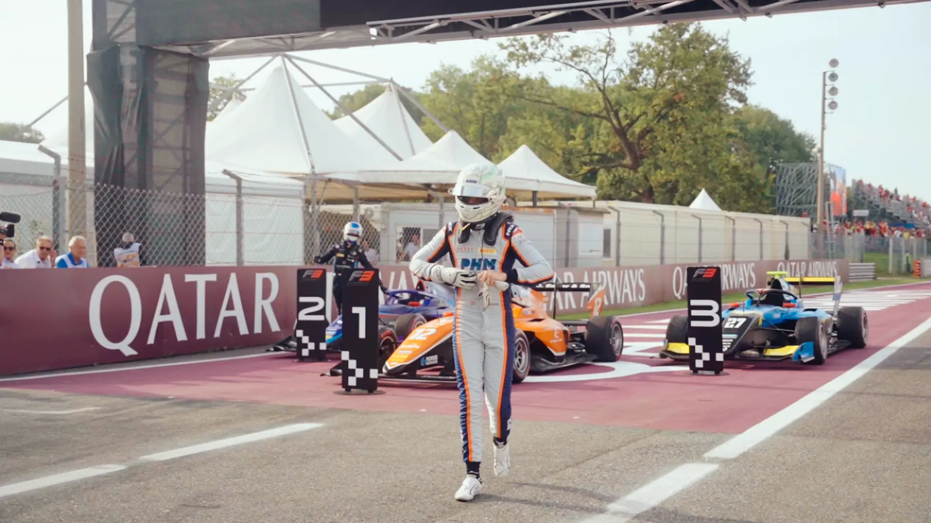 Race driver walking on podium at F3 Monza circuit with PHM livery cars